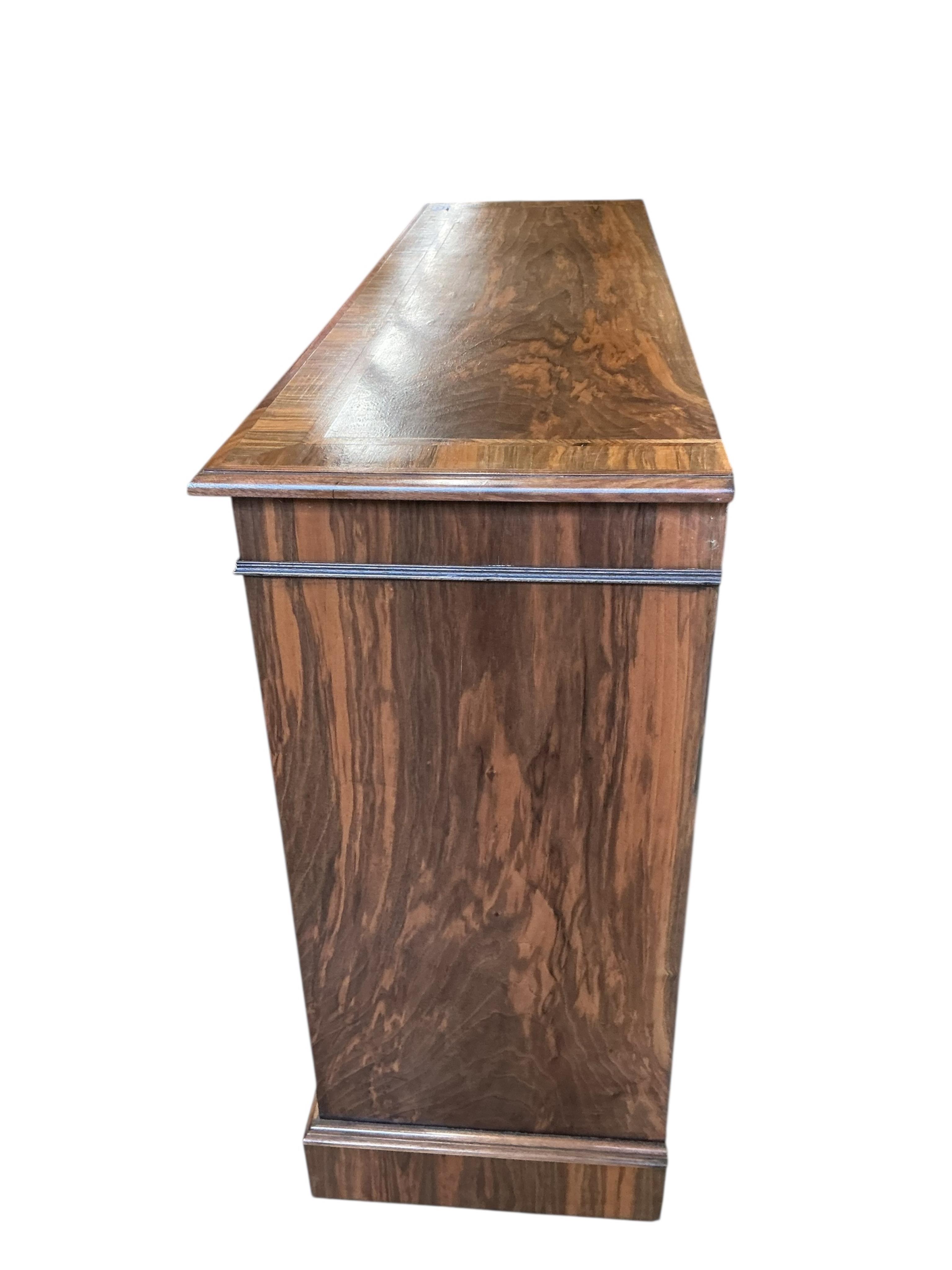 A Regency style feather banded walnut dwarf open bookcase, width 140cm, depth 42cm, height 94cm